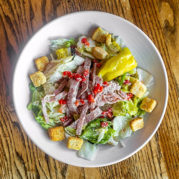 A Marquarts Landing Inc. bar-and-grill salad with lettuce, ham, croutons, red peppers, and a yellow pepper.