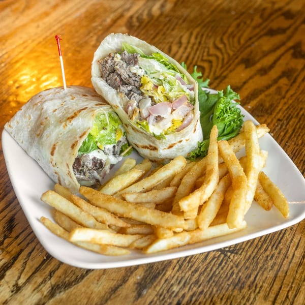 A Marquarts Landing Inc. steak wrap with lettuce, onions, and sauce, served with golden fries.