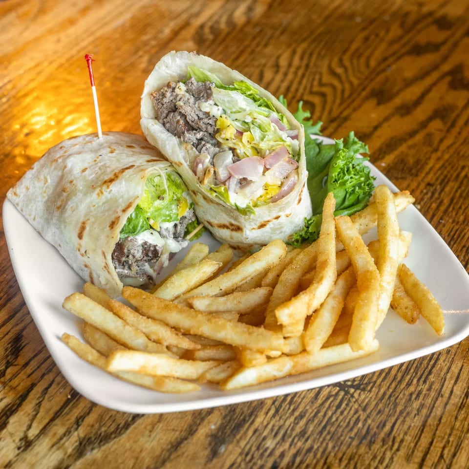 A Marquarts Landing Inc. steak wrap with lettuce, onions, and sauce, served with golden fries.