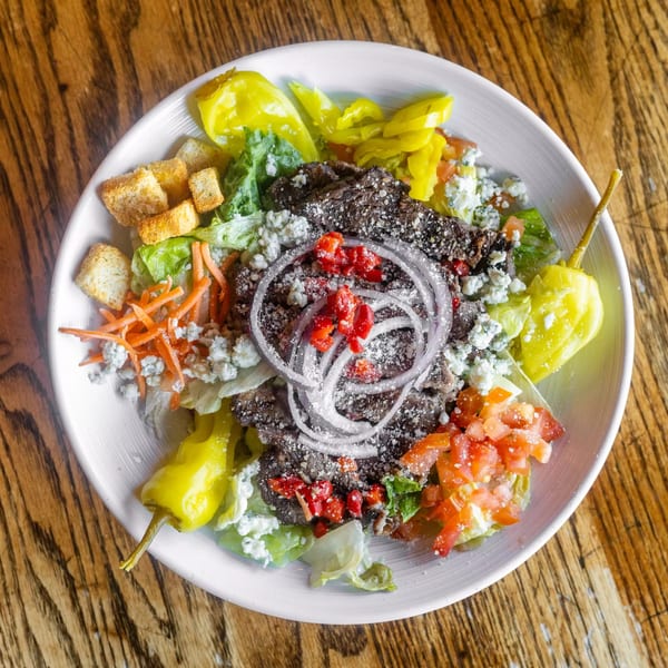 Overhead view of a Marquarts Landing Inc. bar-&-grill salad with meat, cheese, and vegetables.